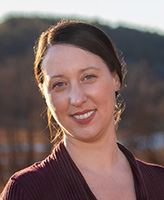 a smiling headshot of Tori Rosati, a middle aged woman with a big smile and dark hair parted on her right side