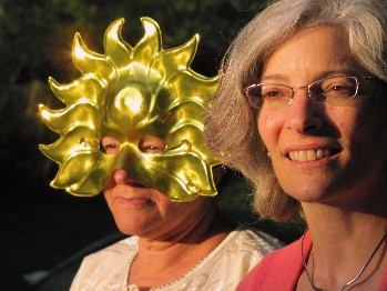 two women performing in the solstice celebration, one wearing a sun mask 