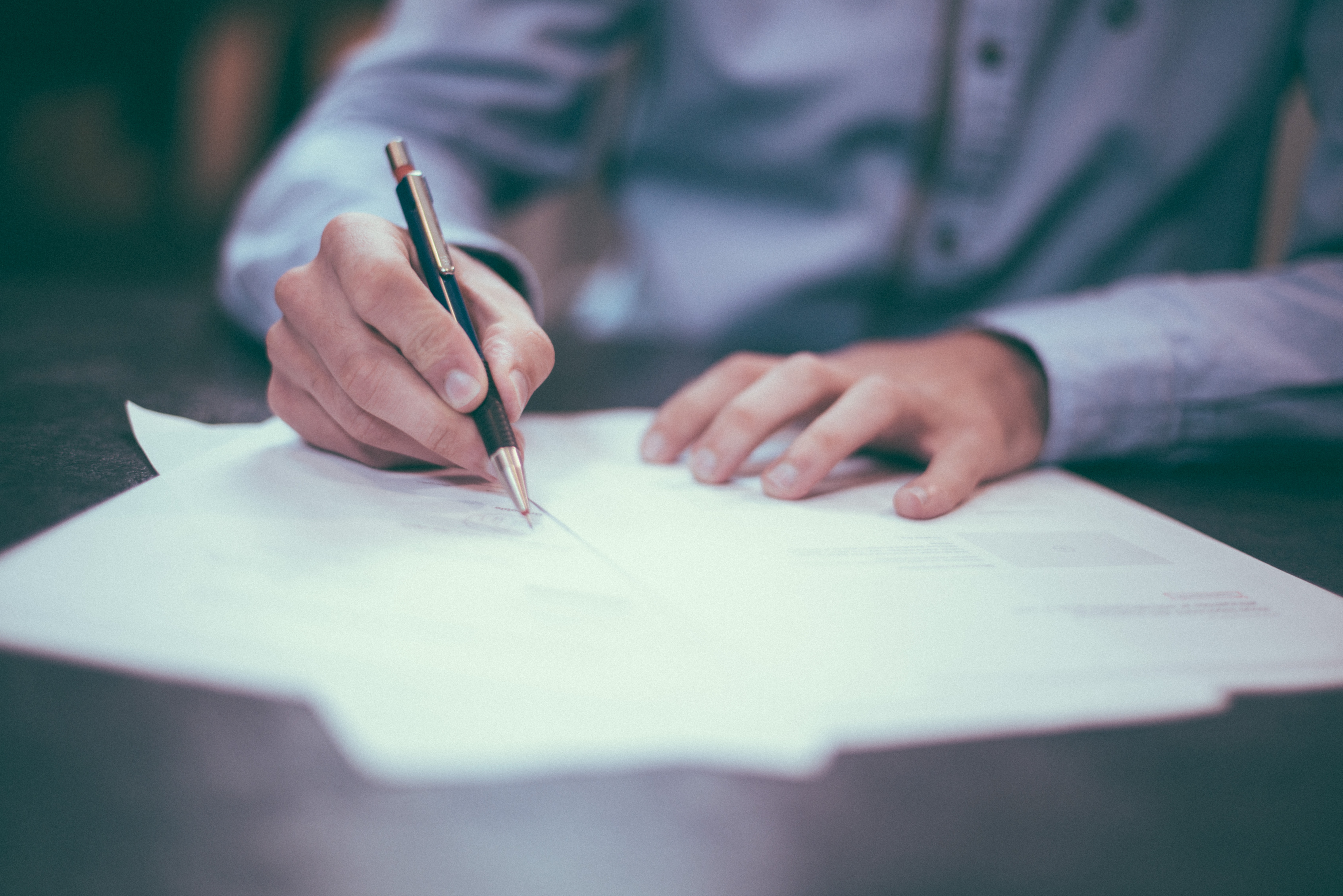 the arms of a man writing legal documents at a desk